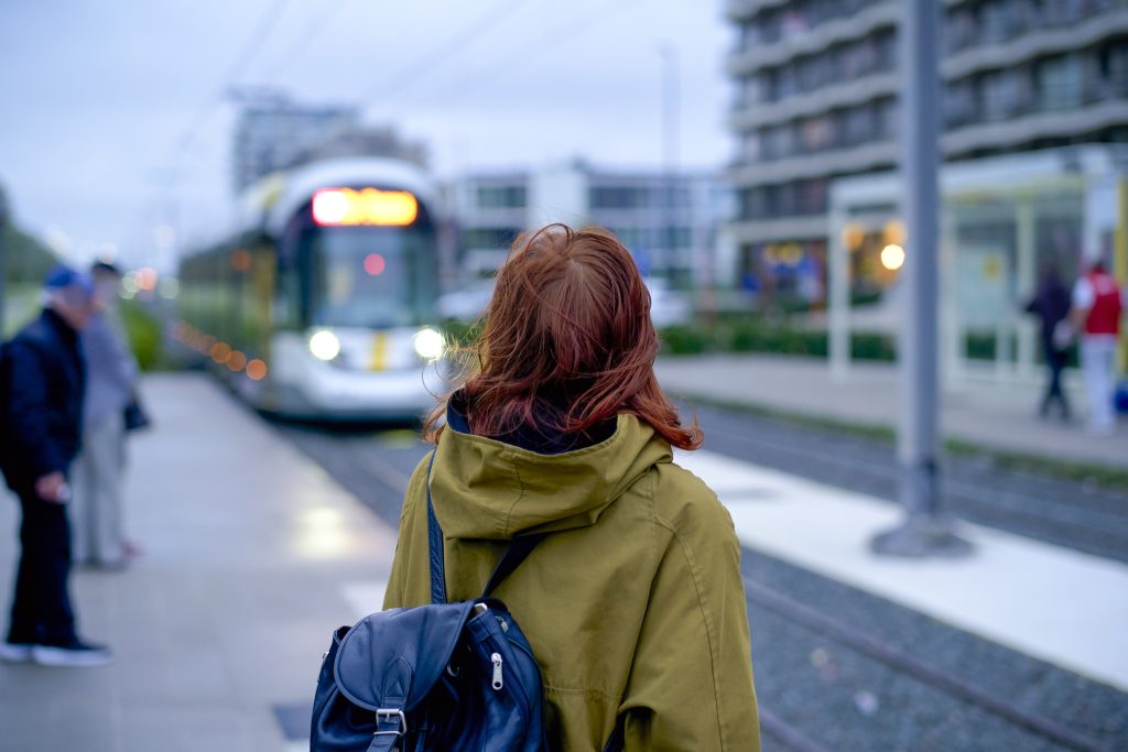 JobTram in Mainz: Frau wartet an der Haltestelle, während eine Straßenbahn einfährt